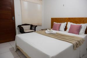 a bedroom with a large bed with pink and white pillows at Araruna Hotel in Araruna +2 photos