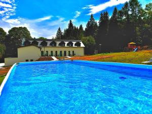 a large blue swimming pool in front of a house at Paseky Wellness Apartments Resort - bazén, sauna, vířivka in Nové Město na Moravě