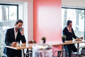 a man sitting at a table talking on his cell phone at Stay Hotel Porto Centro Trindade in Porto