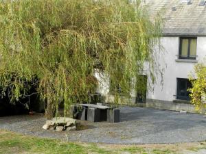 a tree in front of a house with a table under it at Gîte La Part des Anges in Saint-Angel