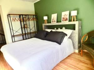 a bedroom with a white bed with a green wall at Gîte La Part des Anges in Saint-Angel