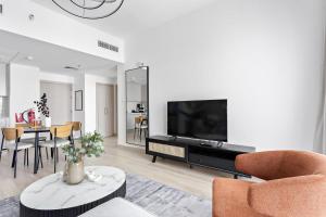uma sala de estar com televisão e mesa com cadeiras em Silkhaus Luxury 1BDR with easy access to the Canal em Abu Dhabi