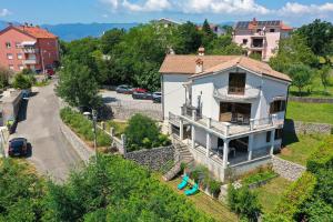 a white house with a balcony and a parking lot at Apartman Kalinda in Rijeka