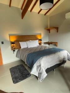 a bedroom with a large bed with two lamps and a rug at Altos da Mantiqueira Grupo Vertentes in Santo Antônio do Pinhal