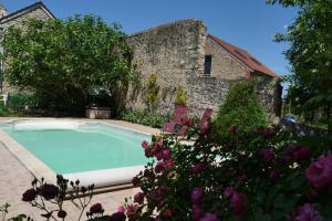 a swimming pool in front of a building with flowers at Le Nid du Cormier in Ville-Saint-Jacques