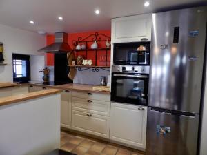 a kitchen with white cabinets and a stainless steel refrigerator at Gîte La Part des Anges in Saint-Angel +34 photos