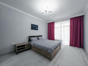 a bedroom with a bed with red curtains and a chandelier at Hotel Utes in Kaji-Say