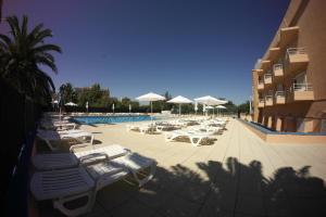 a pool with white lounge chairs and umbrellas at Nautilus Hotel in Roses