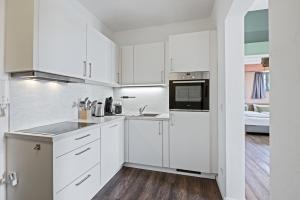 a white kitchen with white cabinets and appliances at Hafenlodge - Urlaub im Denkmal in Wismar