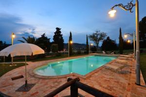a swimming pool with an umbrella and chairs in a yard at Casa Vacanze Residenza Bocci in Foligno