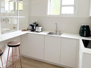 une cuisine avec des armoires blanches et un évier dans l'établissement La Buganvilla, à Chiclana de la Frontera