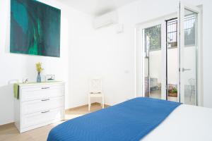 a white bedroom with a blue bed and a dresser at Casa Stella in Vico Equense