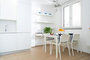 a white kitchen with a white table and chairs at Casa Stella in Vico Equense