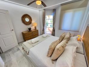 Un dormitorio con una cama blanca con almohadas y una ventana. en Polarsol153, en Mijas Costa 25 fotos más