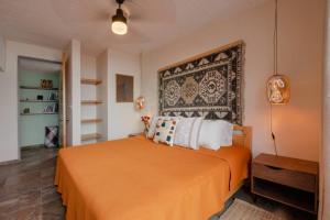 a bedroom with a bed with an orange blanket at Casa Tiptón - Artsy in the City in Oaxaca City