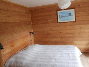 a bedroom with a bed in a wooden room at Appartement RDC chalet 55m2 in Briançon