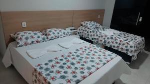 two beds in a hotel room with a bedspread and pillow at Pousada Kactus in Piranhas