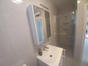 a white bathroom with a sink and a shower at Apartman Dina in Peroj