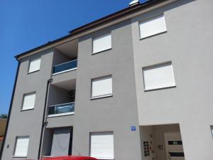 an exterior view of a building with white windows at Apartman Dina in Peroj