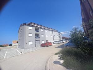 a large building with cars parked in a parking lot at Apartman Dina in Peroj