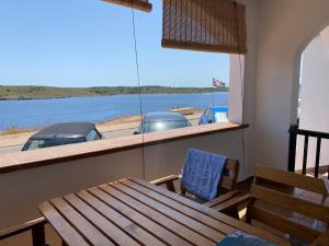 a table and chair in a room with a view of a boat at CARACOLA by SOM Menorca in Fornells