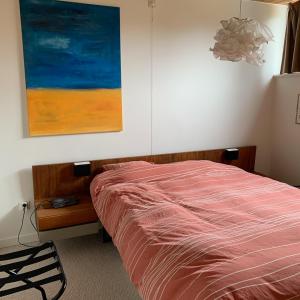 ein Schlafzimmer mit einem Bett und einem Gemälde an der Wand in der Unterkunft Vintage Vakantiebungalow in Oostduinkerke in Koksijde