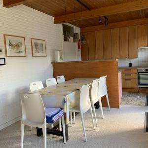 ein Esszimmer mit einem Tisch und weißen Stühlen in der Unterkunft Vintage Vakantiebungalow in Oostduinkerke in Koksijde