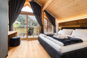 a bedroom with a large bed and a large window at Chalet Lumis in San Vigilio Di Marebbe