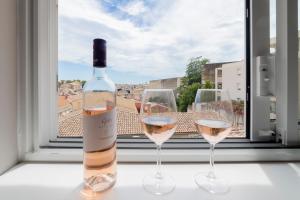 - une bouteille de vin et deux verres devant une fenêtre dans l'établissement Le Belvédère Nîmois proche centre ville Clim &Véranda MaisonCarréeConciergerie, à Nîmes 13 autres photos