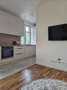 a kitchen with white cabinets and a flat screen tv at Suncity apartamentai in Šiauliai