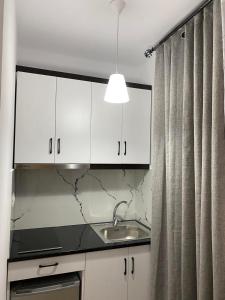 a kitchen with white cabinets and a sink at Rentrooms Geni in Ksamil