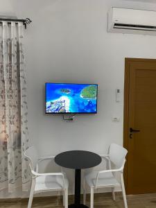 a tv on a wall with a table and chairs at Rentrooms Geni in Ksamil