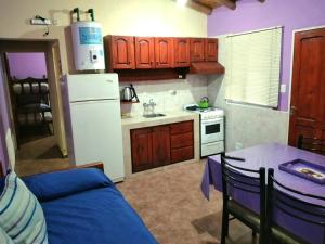 a kitchen with a table and a white refrigerator at Cabañas Barricas de Roble en San Rafael in San Rafael