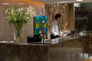 a man standing at a counter in a room with flowers at Hotel Punta del Este in Mar del Plata