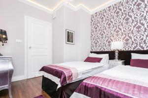 2 camas en una habitación con paredes blancas y papel pintado en Executive 2-bedroom Apartment, en Cracovia