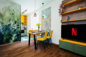 a dining room with a tv and a table with yellow chairs at Jungle Apartment chill&bed Zator in Zator +21 photos