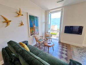 a living room with a green couch and a tv at Immobillario - Domus Palmae in Domaso