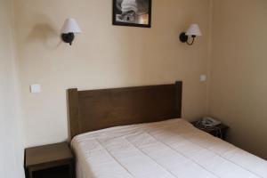 a bed in a bedroom with two lights on the wall at appartement 5 places à VARS in Vars