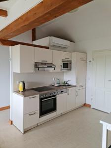 a kitchen with white cabinets and a stove top oven at Monteurwohnung SEEBLICK AUSBLICK 16356 Werneuchen bei Berlin in Werneuchen