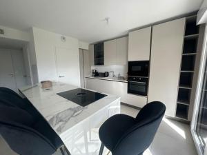 a white kitchen with two black chairs and a counter at Clos d'Alice Villa 3 in Sainte-Maxime