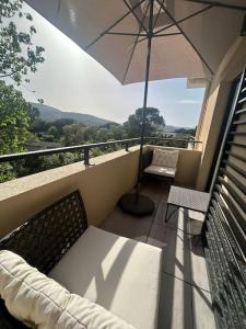 a balcony with an umbrella and a couch and chairs at Clos d'Alice Villa 3 in Sainte-Maxime