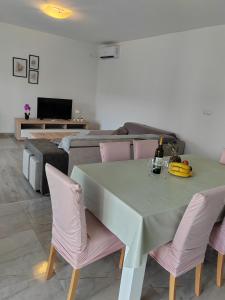 a dining room with a green table and pink chairs at Apartmani Dubravka in Rab