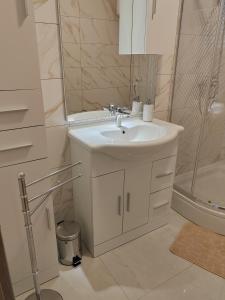 a white bathroom with a sink and a shower at Apartmani Dubravka in Rab