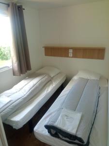 two beds in a small room with a window at Camping de Marcilly sur Vienne in Marcilly-sur-Vienne