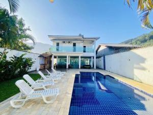 a villa with a swimming pool and lounge chairs at Sua Casa em Maresias I in São Sebastião