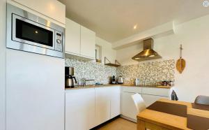 a kitchen with white cabinets and a wooden table at Les Adrets de Malmedy in Malmedy