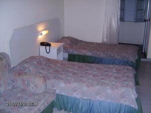 um quarto de hotel com duas camas e uma cadeira em Olhos Pretos em Caldas da Rainha