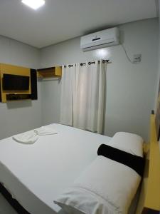 una camera da letto con un letto bianco e una finestra di FLAT Residencial Caribe a Confresa