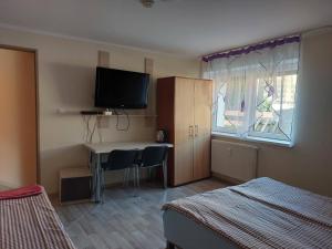 a bedroom with a desk with a television and a window at NOCLEGI u ALI in Wałbrzych