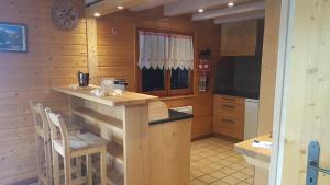 eine Küche mit einer Theke und Stühlen in einer Hütte in der Unterkunft Chalet Les Bouvreuils La Bresse Haute Vosges in La Bresse